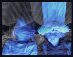 Abstrakcyjna fotografia dziecka oraz zamazanej postaci, oświetlonych na niebiesko. Ciemne tło.